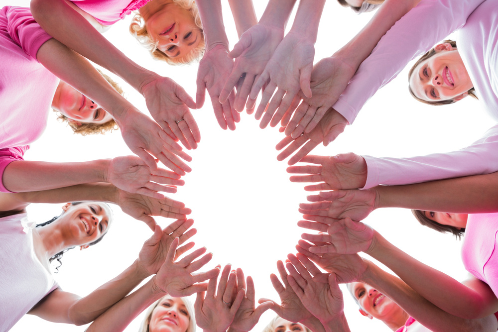 Happy women in circle wearing pink for breast cancer on white background